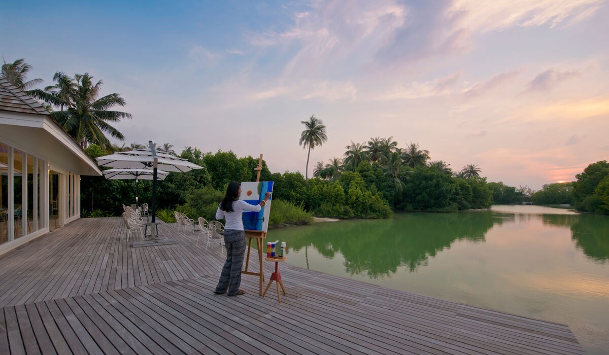 A woman painting in front of Aroma Lake at Kandima Maldives